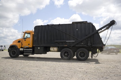 Skip hire vehicle and crew preparing a skip on a city street